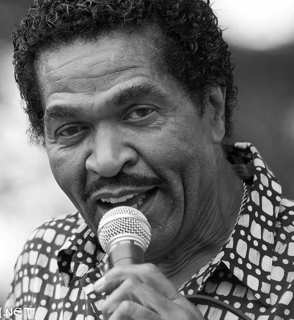 A close up of Bobby Rush holding a microphone and crooning to the camera