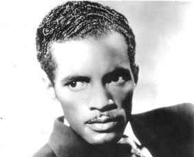 A portrait of Percy Mayfield in a suit and tie. He looks off into the distance.