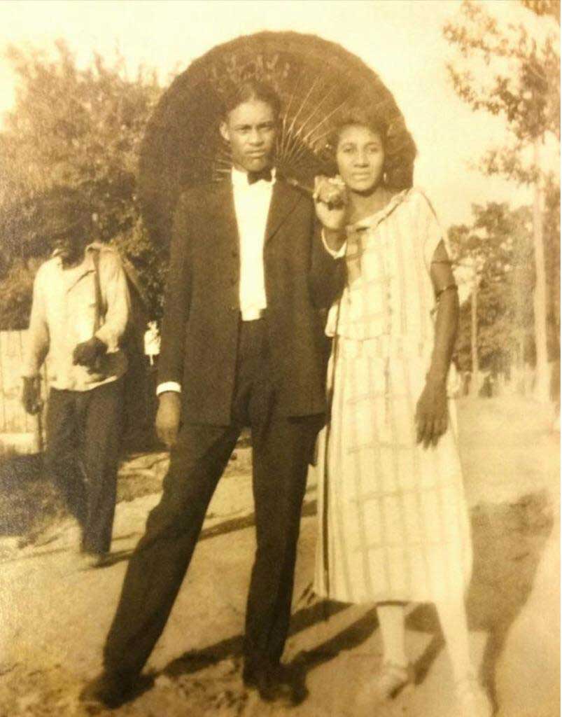Son and a woman pose under a parasole in a sepia-toned outdoor setting