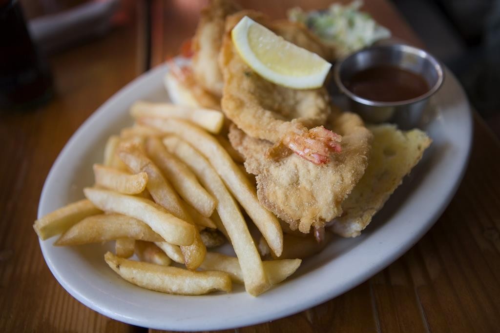 An open-faced fried shrimp sandwich next to golden french fries at Herby K’s restaurant.