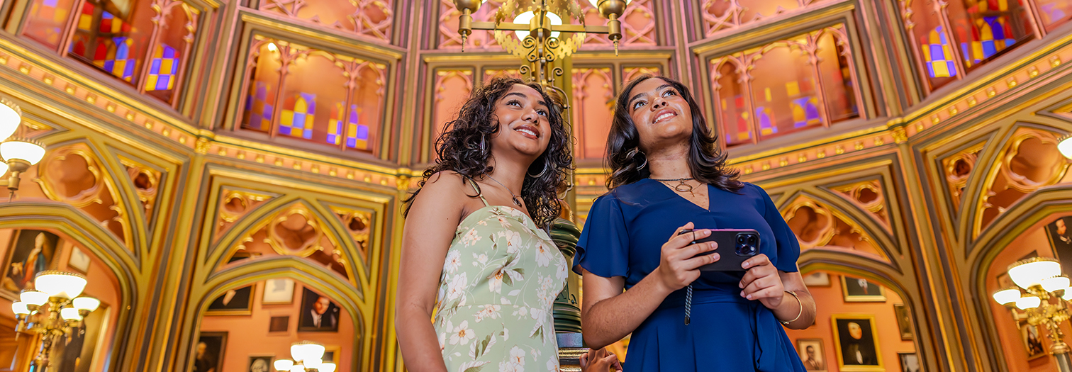 Two travelers look at cathedral-like stained glass inside Louisiana's Old State Capitol.