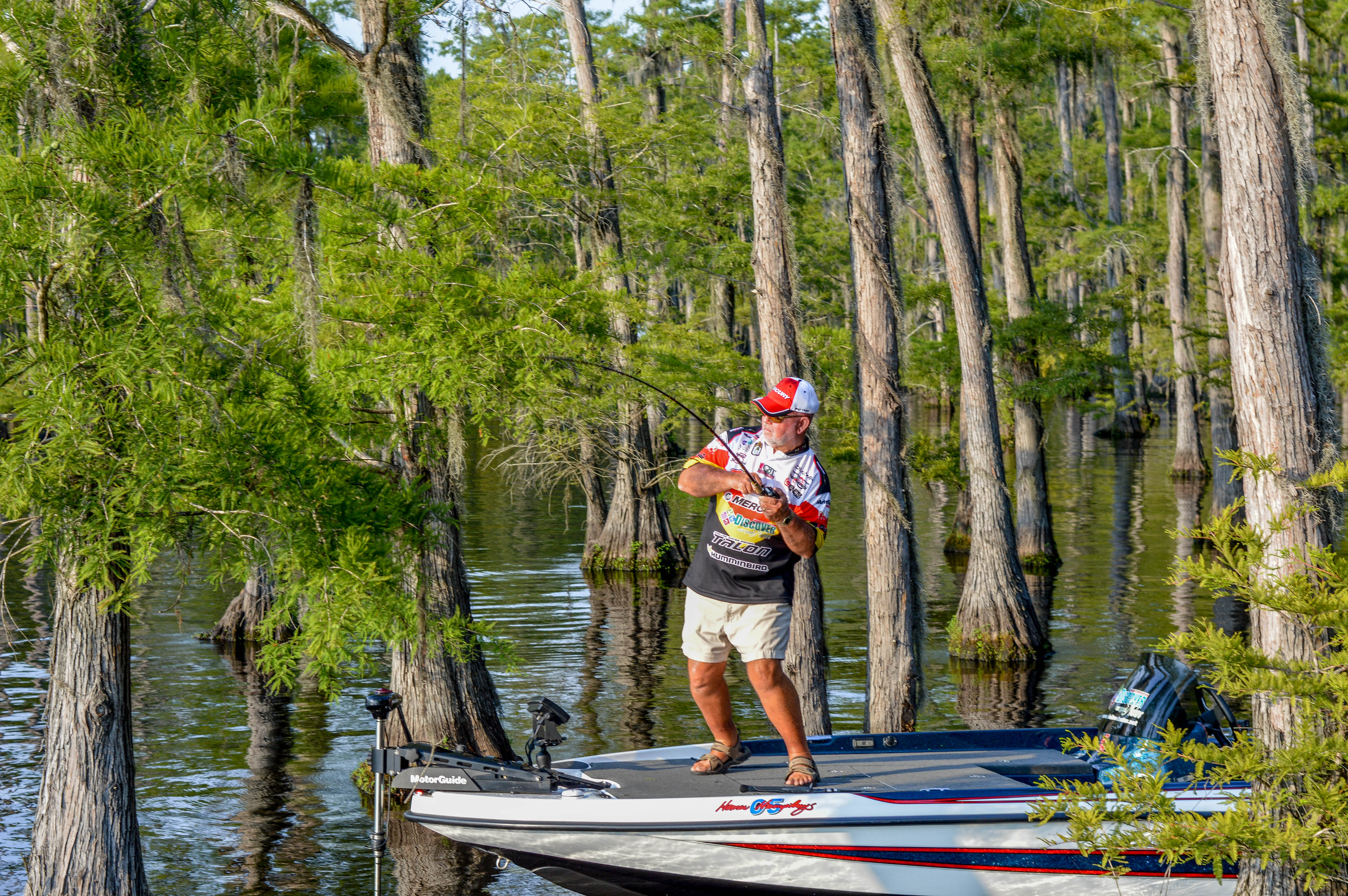 A man fishes from a boat in the bayou
