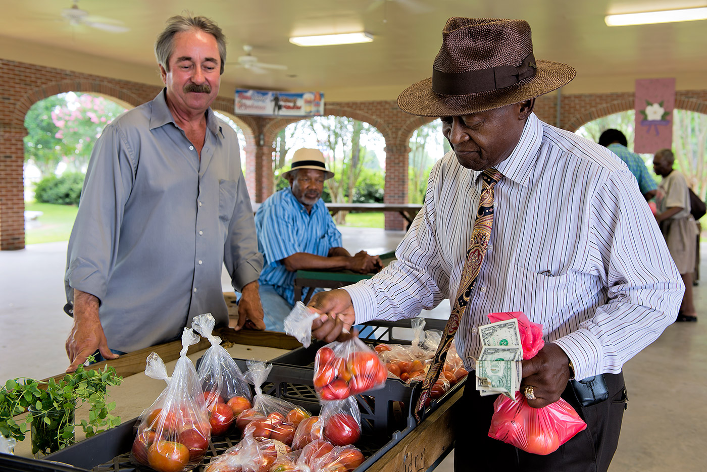 A vendor and shopper holding bags of apples at the Opelousas Farmers Market in Louisiana.