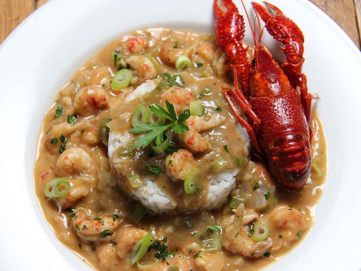 Crawfish étouffée over rice, topped with a bright red crawfish in its shell.