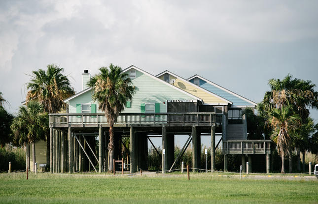 Turquoise, yellow and blue cabins on stilts at Cypremort Point State Park.