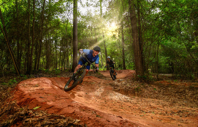 Two people enjoy the muddy mountain-biking trails at Bogue Chitto State Park.