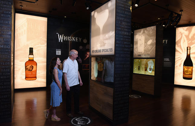 Visitors wandering through a glowing exhibit at the Sazerac House Museum in New Orleans, Louisiana.