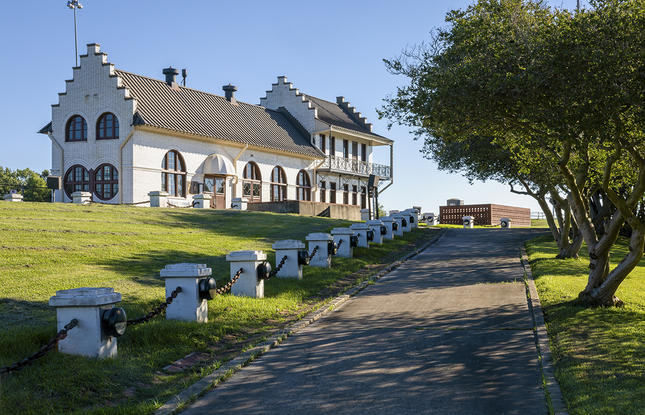 Driveway leading up to a large white building on a hill with unique architectural features