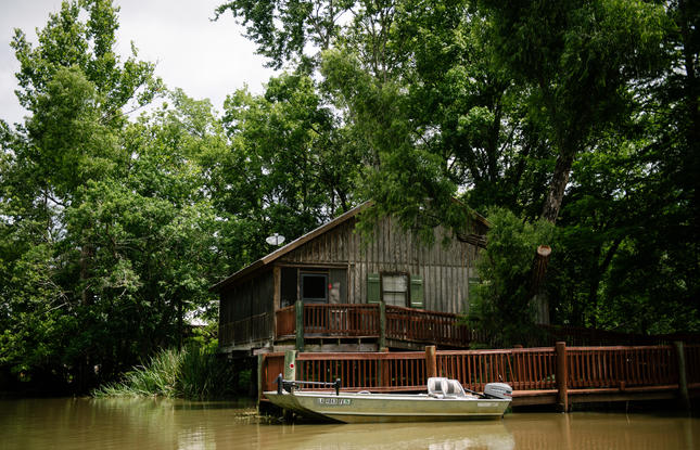 A fishing boat is docked at a cozy, wetland architecture-inspired cabin at Lake Fausse Pointe State Park.