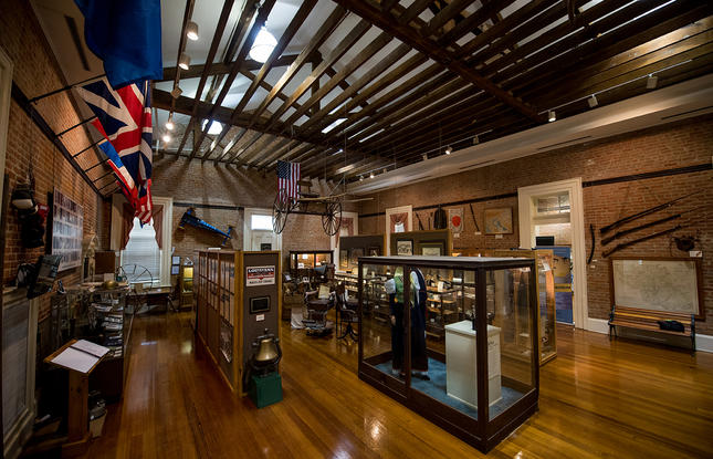 Interior of a museum with wooden floors and beams, with exhibits and displays behind glass
