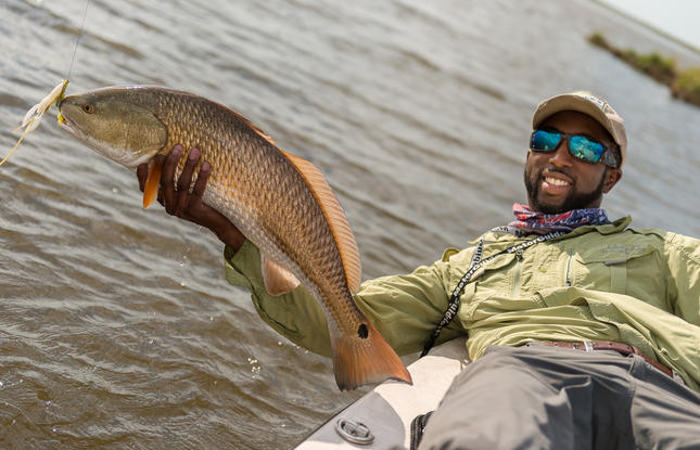 A man leaning over a boat and holding a large fish.