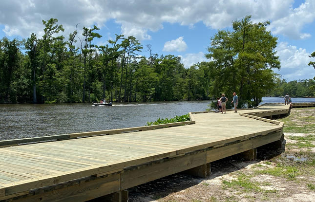 People walk along the boardwalk at Sam Houston Jones State Park.