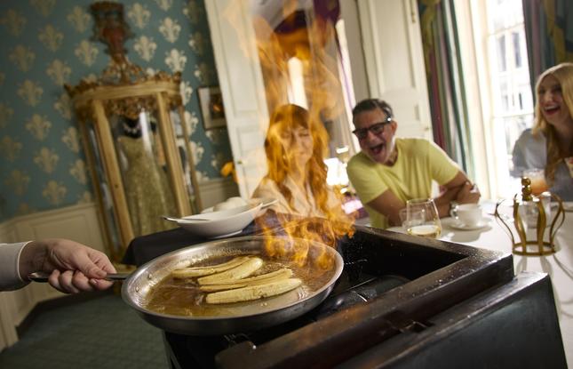 A table of diners look on excitedly as bananas foster are made table side at Brennan's.