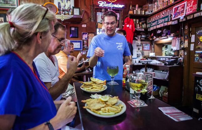 A server explains a dish to a couple seated at the bar of a Shreveport restaurant.