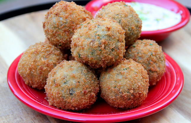 Golden-fried boudin balls sit on a red plate.