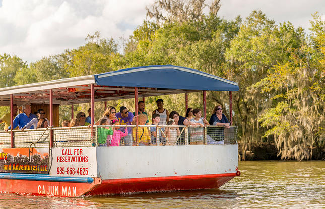 The Cajun Man swamp tour boat, filled with visitors of all ages enjoying a swamp tour in Louisiana.