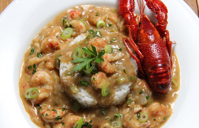 Crawfish étouffée over rice, topped with a bright red crawfish in its shell.