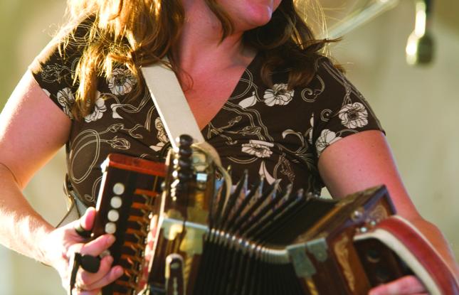 A woman playing an accordion on stage at the Festival Acadiens et Creoles in Lafayette.