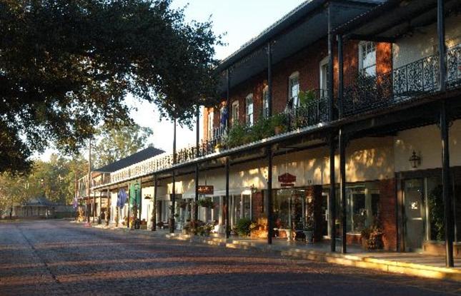 Picturesque Historic Front Street in Natchitoches features balconies lined with greenery and fairy lights.