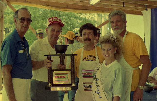 The winning team of the 1986 Jambalaya Festival holding a trophy and smiling for the camera.