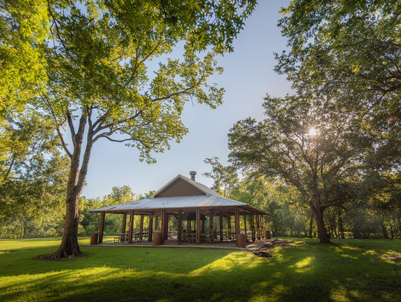 The group pavilion at St. Bernard State Park sits on a green, grassy hill, surrounded by trees.