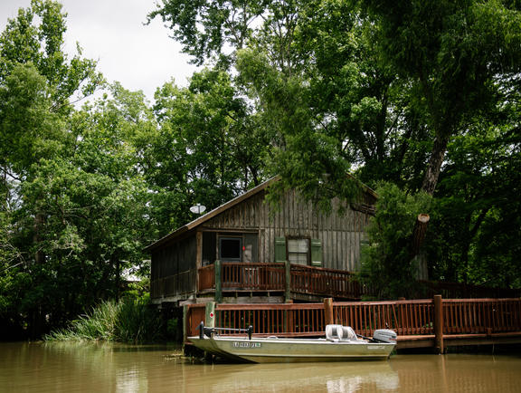 A fishing boat is docked at a cozy, wetland architecture-inspired cabin at Lake Fausse Pointe State Park.
