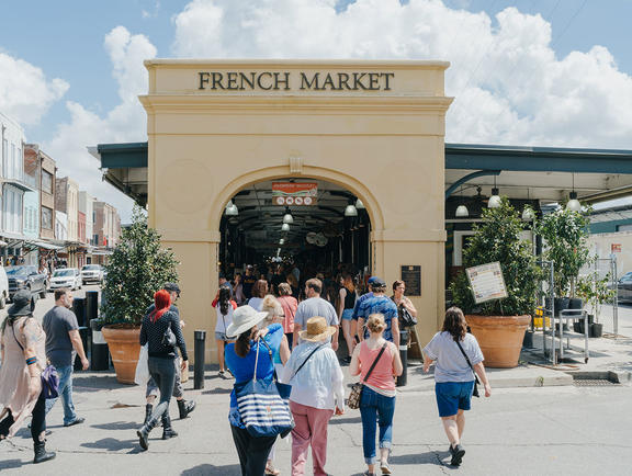 A large archway making the entrance to the French Market in New Orleans, Louisiana, surrounded by people shopping.