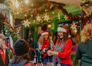 people serve wine at a Christmas Art Walk event in Louisiana