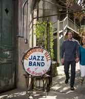 A young Couple walking by Louisiana Preservation Hall and a round sign says Jazz Band
