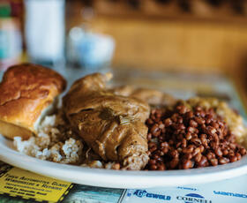 White plate of soul food piled with beans, rice and bread