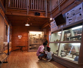 A parent and child kneel in front of a display of military artifacts at Louisiana Maneuvers and Military Museum in Pineville.