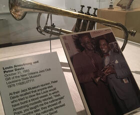 Museum display of a cornet instrument and a picture of two musicians