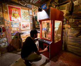 A person kneels to play an arcade game at the Abita Mystery House.