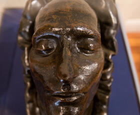 A bronze death mask of a face in a museum exhibit