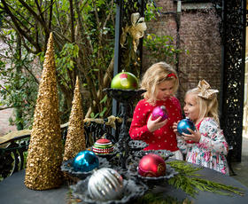Two children hold round Christmas tree ornaments at the Biedenharn Museum &amp; Gardens Christmas celebration.