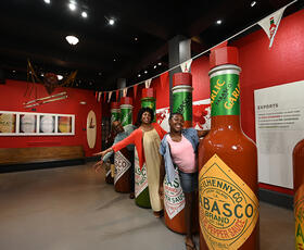 Two women pose with giant bottles of Louisiana-born TABASCO hot sauce.