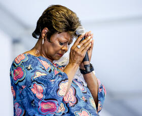 Irma Thomas folds her hands over her microphone in prayer at Jazz Fest.