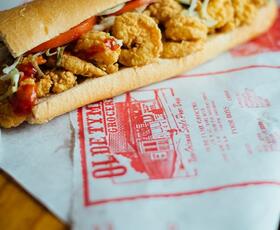 A fried shrimp poor boy sandwich on deli wrapping paper