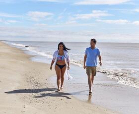 A man and woman walk along the shore of Holly Beach in Louisiana.