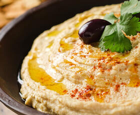 A bowl of hummus with olive oil and an olives from Athena Restaurant in Monroe
