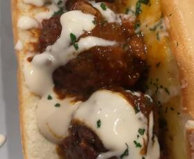 A vegan meatball sub covered in white sauce from Creole Hidden Garden in Lake Charles