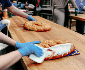 A baker ices a king cake with frosting.