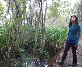 A woman in a blue jacket and black rainboots gazes at the surrounding nature in Mandalay National Wildlife Refuge.