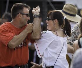 A man in an orange shirt dances with a woman in a white shirt.