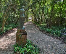 A grayish green statue stands at the entrance to a trail at the Audubon Historic Site.