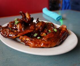 A plate of glazed barbecue ribs garnished with chopped green onions, served on a teal table.