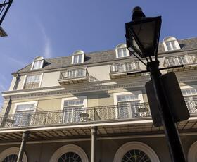 The exterior of the Bourbon Orleans, with wrought-iron balconies, softly lit by sunlight.