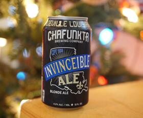 A can of “Invinceible Ale” from Chafunkta Brewing Company, with a tree lit with twinkling lights in the background.