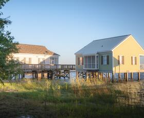 Stilted pastel cabins overlooking Lake Pontchartrain at Fontainebleau State Park during golden hour.
