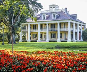 Houmas House plantation with white columns and manicured gardens in the foreground.